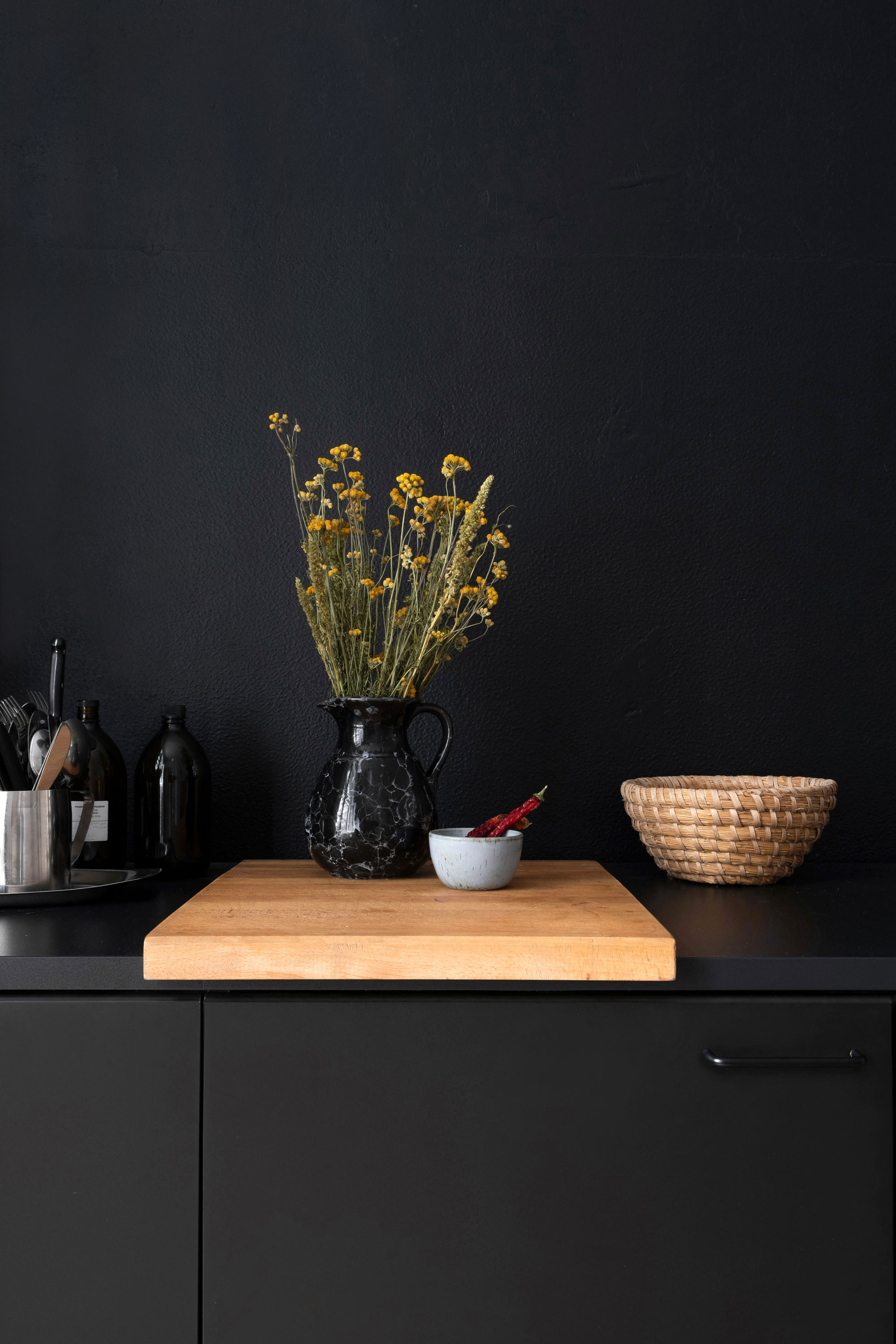 Fotografie eines Stilllebens, Blumen in einer Vase vor schwarzer Wand